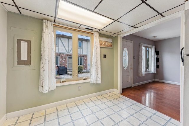 entryway featuring electric panel, a paneled ceiling, baseboards, and wood finished floors