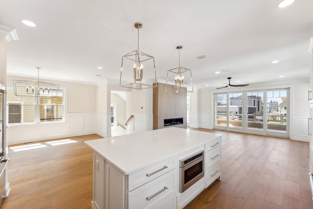 427 E 5th Ave, North Wildwood, NJ 08260 - kitchen with stainless steel microwave, open floor plan, a decorative wall, light wood-style flooring, and a chandelier
