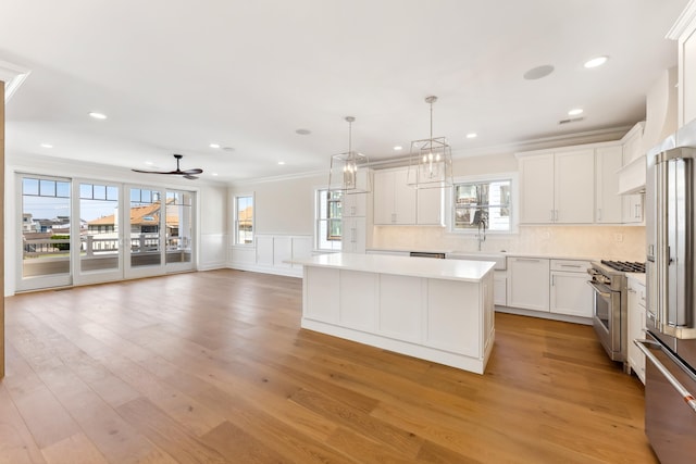 427 E 5th Ave, North Wildwood, NJ 08260 - kitchen featuring premium appliances, crown molding, light countertops, light wood-type flooring, and a kitchen island