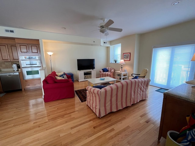 living room featuring ceiling fan, plenty of natural light, and light hardwood / wood-style flooring