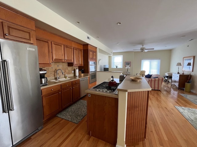 kitchen featuring stainless steel appliances, a kitchen island, sink, and light hardwood / wood-style flooring