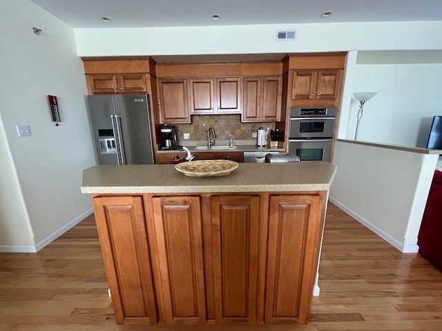 kitchen with appliances with stainless steel finishes, backsplash, a kitchen island with sink, and sink