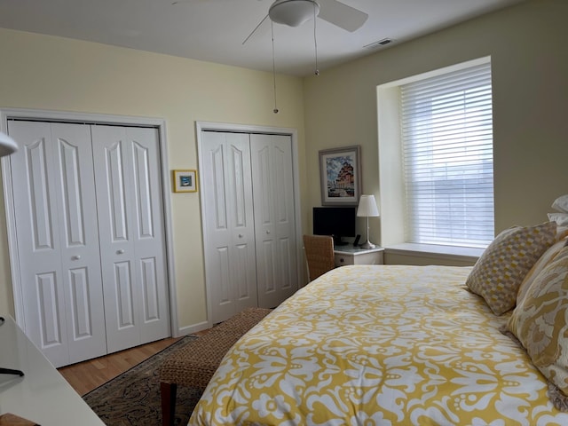 bedroom featuring two closets, ceiling fan, and hardwood / wood-style floors