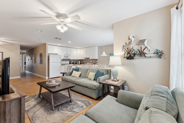 living room featuring ceiling fan and light hardwood / wood-style floors