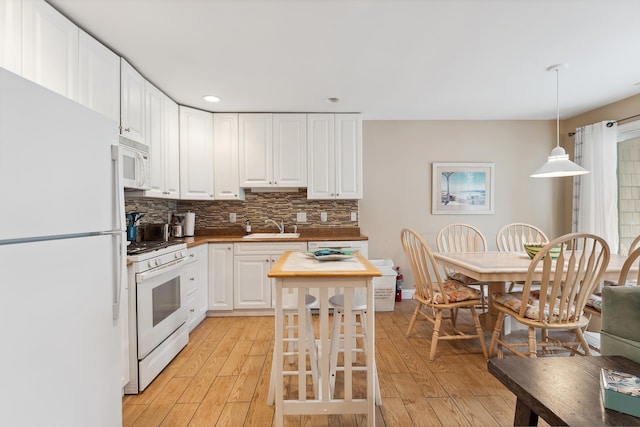 kitchen featuring sink, white cabinets, decorative light fixtures, and white appliances