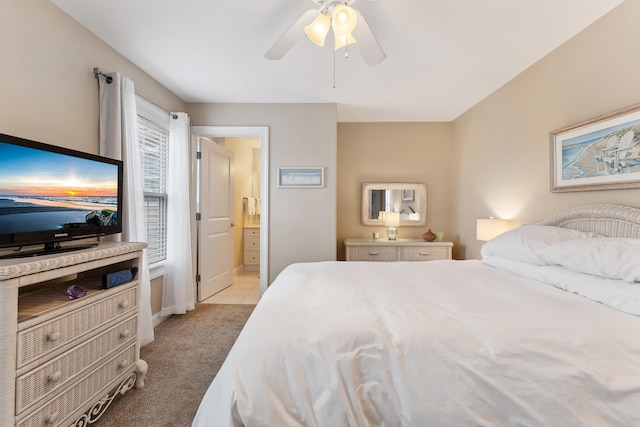 bedroom with light carpet, ensuite bath, and ceiling fan