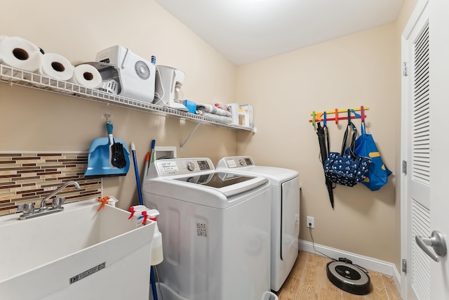 laundry area with washing machine and dryer, sink, and light hardwood / wood-style floors