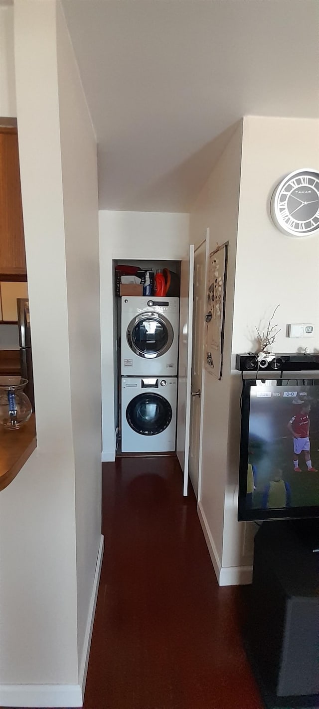 hallway with estacked washer and dryer and baseboards