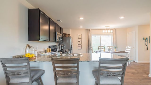 kitchen featuring stainless steel appliances, a breakfast bar area, and light stone counters