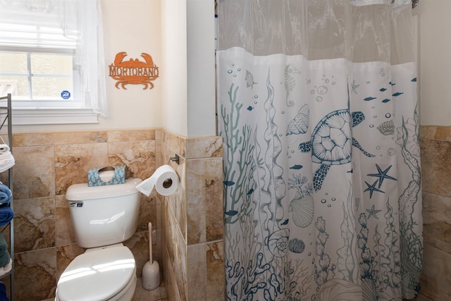 bathroom with toilet, curtained shower, and tile walls