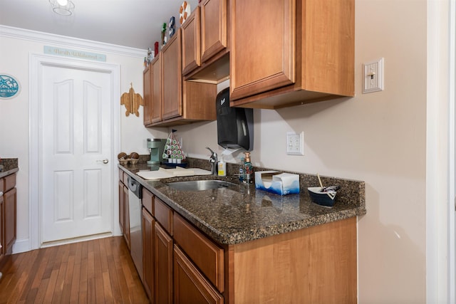 kitchen with stainless steel dishwasher, dark stone counters, crown molding, sink, and hardwood / wood-style floors