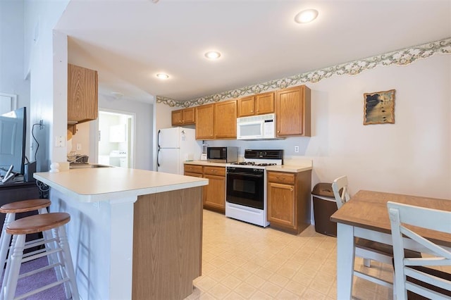 kitchen featuring a breakfast bar area, kitchen peninsula, and white appliances