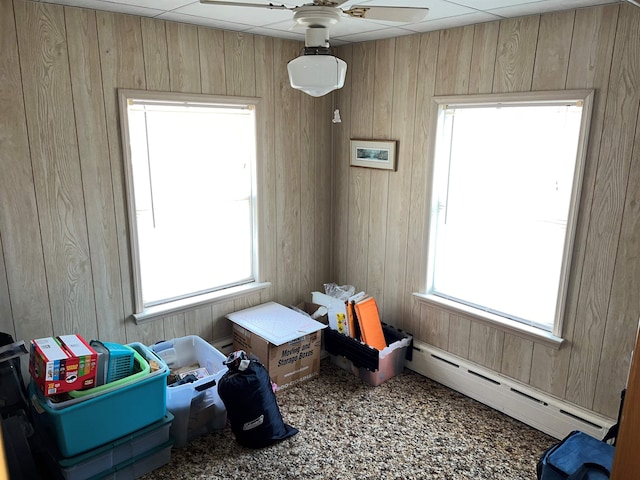 carpeted bedroom with multiple windows, baseboard heating, wooden walls, and a paneled ceiling