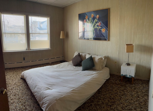 bedroom featuring a baseboard radiator, carpet flooring, and wood walls