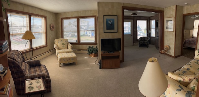 living area with carpet flooring, a wealth of natural light, and a baseboard heating unit