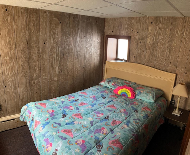 carpeted bedroom featuring wood walls and a paneled ceiling