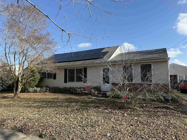 ranch-style home with a front yard and solar panels