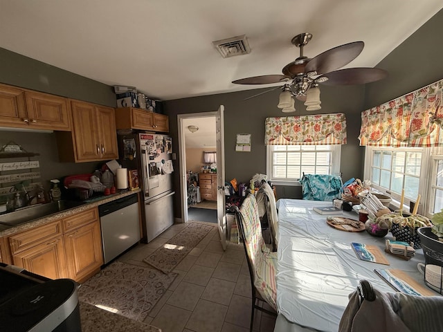 kitchen with appliances with stainless steel finishes, ceiling fan, dark tile patterned floors, and sink