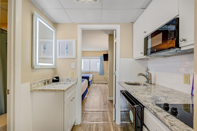 kitchen featuring black appliances, a paneled ceiling, white cabinetry, and sink