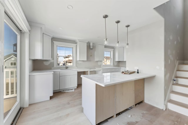 kitchen with white cabinets, decorative light fixtures, kitchen peninsula, and sink