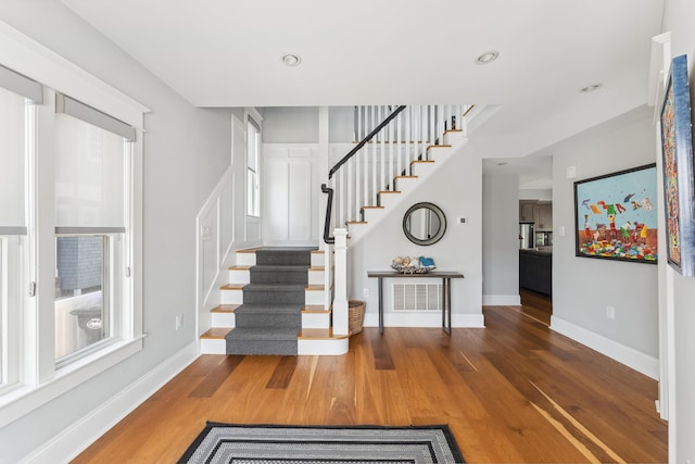 stairs featuring wood finished floors, baseboards, and recessed lighting