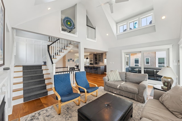 living room featuring wood finished floors, stairway, high vaulted ceiling, ceiling fan, and recessed lighting