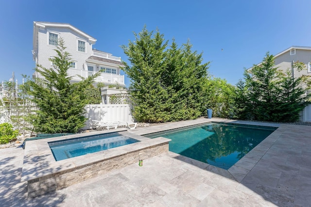 outdoor pool featuring an in-ground hot tub, a patio area, and fence