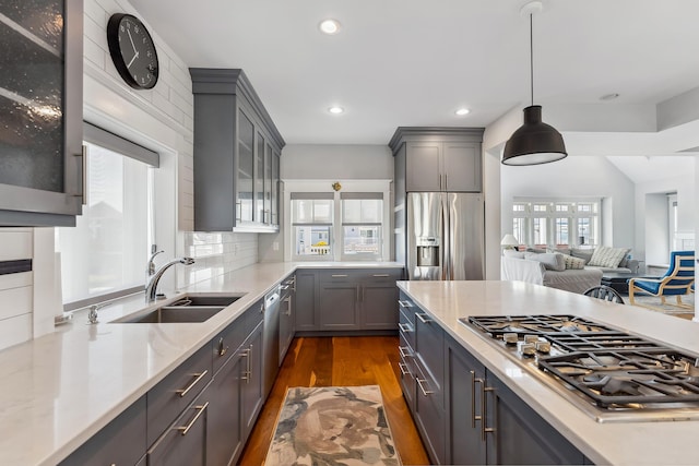 kitchen with stainless steel appliances, a sink, gray cabinetry, dark wood-style flooring, and recessed lighting