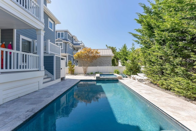 view of swimming pool with a patio area, fence, and a pool with connected hot tub