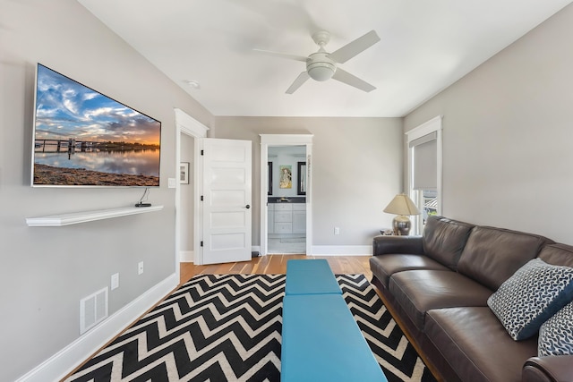 living area featuring a ceiling fan, wood finished floors, and baseboards