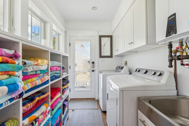 laundry area featuring separate washer and dryer, cabinet space, and wood finished floors