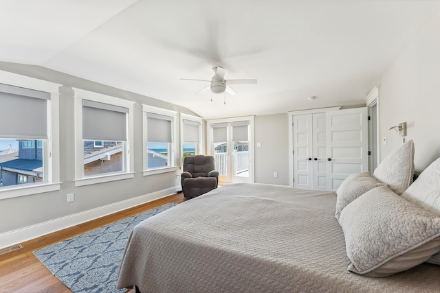 bedroom featuring lofted ceiling, wood finished floors, baseboards, and multiple windows