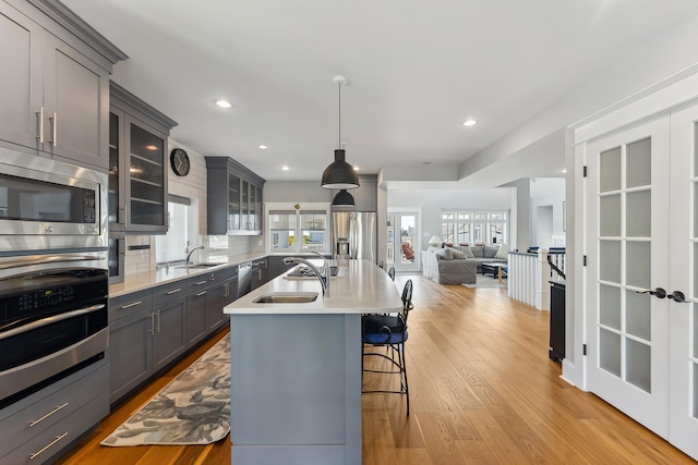 kitchen with gray cabinets, appliances with stainless steel finishes, a sink, light countertops, and open floor plan