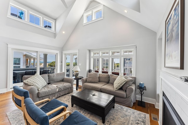 living area with high vaulted ceiling, baseboards, wood finished floors, recessed lighting, and french doors