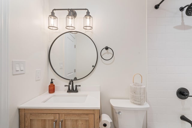 bathroom with tiled shower, vanity, and toilet