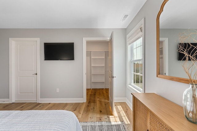 bedroom featuring hardwood / wood-style floors and a walk in closet