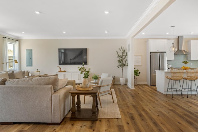 living room featuring crown molding, electric panel, and light hardwood / wood-style flooring