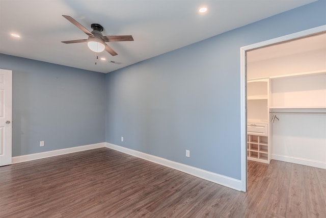 unfurnished bedroom with hardwood / wood-style flooring, a closet, ceiling fan, and a spacious closet