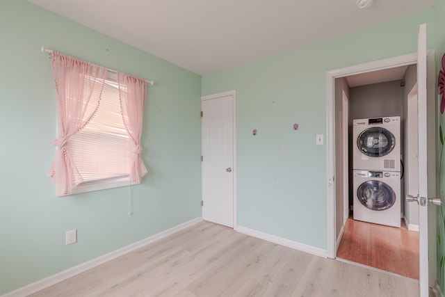 unfurnished bedroom with stacked washing maching and dryer and light hardwood / wood-style floors