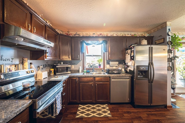 kitchen featuring a textured ceiling, dark brown cabinets, sink, and appliances with stainless steel finishes