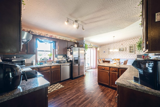 kitchen featuring a textured ceiling, dark hardwood / wood-style flooring, stainless steel appliances, and decorative light fixtures