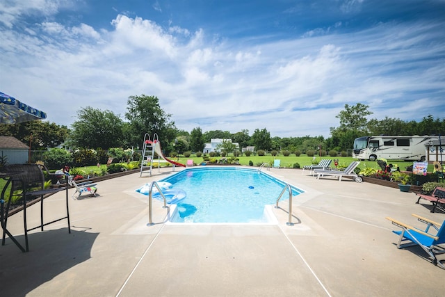 view of swimming pool with a patio area and a water slide