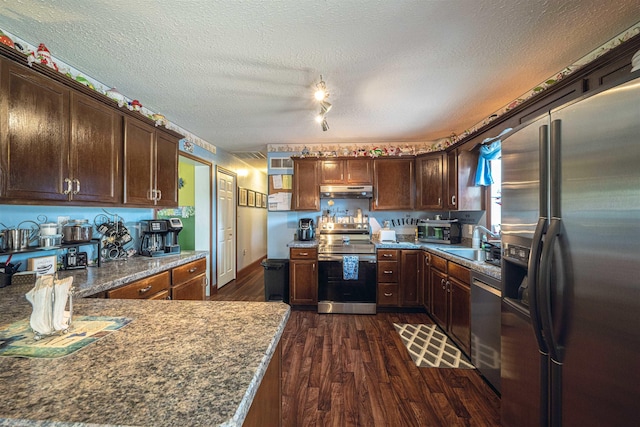 kitchen featuring dark wood-type flooring, sink, a textured ceiling, stone countertops, and stainless steel appliances