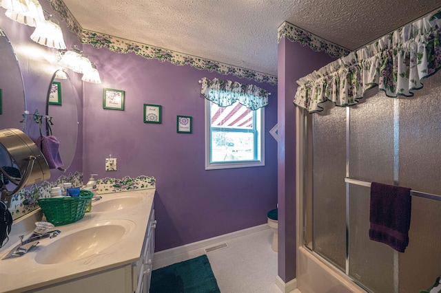 full bathroom featuring vanity, tile patterned floors, combined bath / shower with glass door, toilet, and a textured ceiling