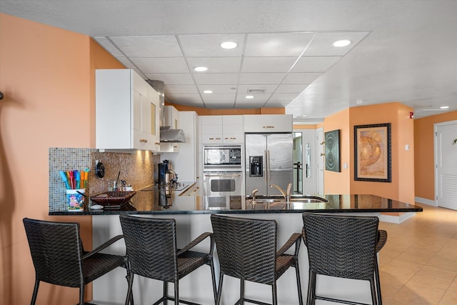 kitchen featuring black appliances, a breakfast bar, white cabinets, and kitchen peninsula