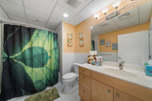 full bathroom with a drop ceiling, vanity, tile patterned floors, toilet, and tile walls