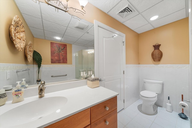 bathroom with tile patterned flooring, vanity, toilet, and tile walls