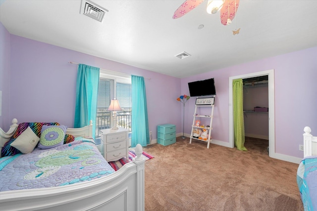 carpeted bedroom with ceiling fan, a walk in closet, and a closet