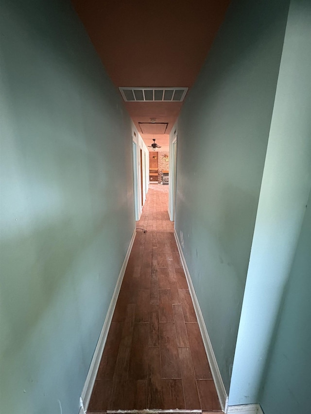 hall with wood finished floors, visible vents, and baseboards