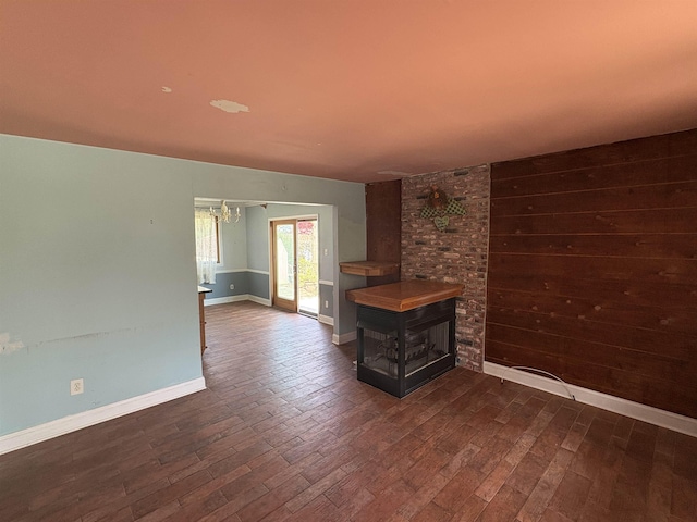 empty room with dark wood finished floors, baseboards, and an inviting chandelier